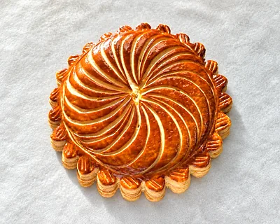 A round pithivier, glazed and scored in a spiral.